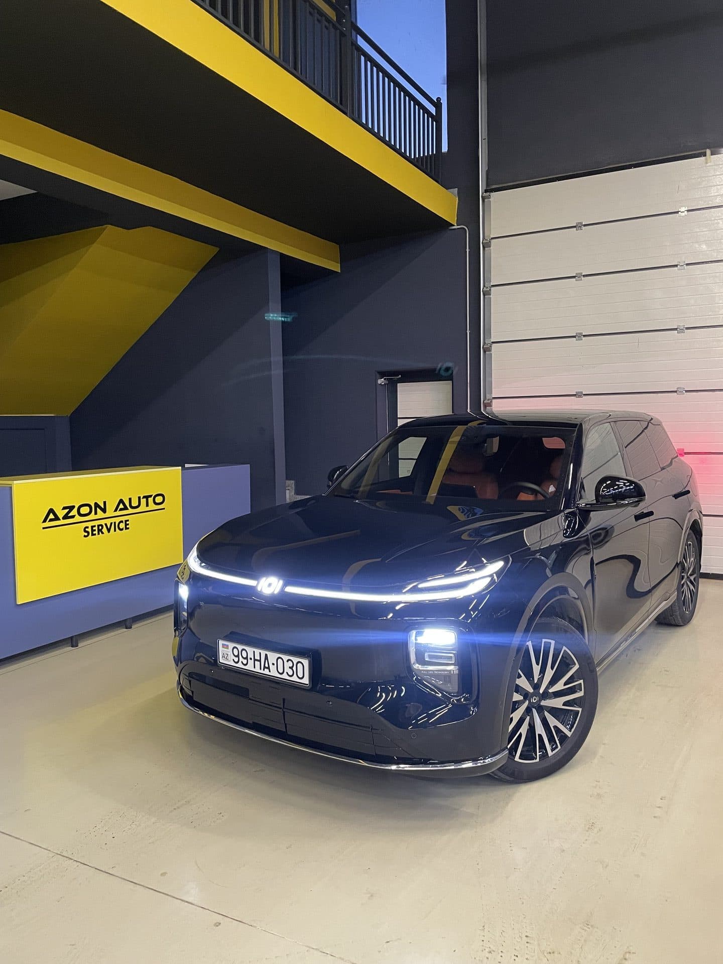 AzonAuto-nun qəbul zonasında tünd göy Li Auto krossoveri, arxada qəbul masası, Bakı