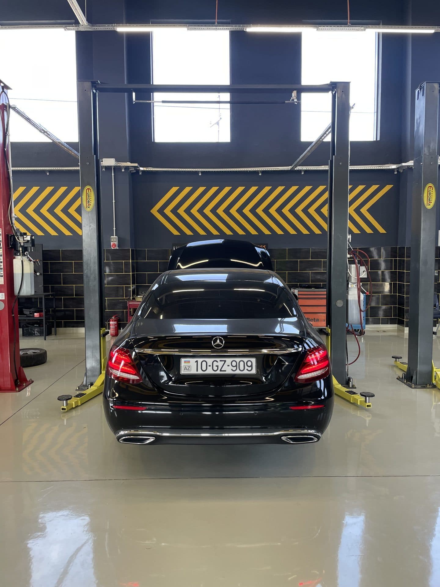 Qaldırıcılar arasında qara Mercedes-Benz E-Class, AzonAuto təmir zalı, Bakı
