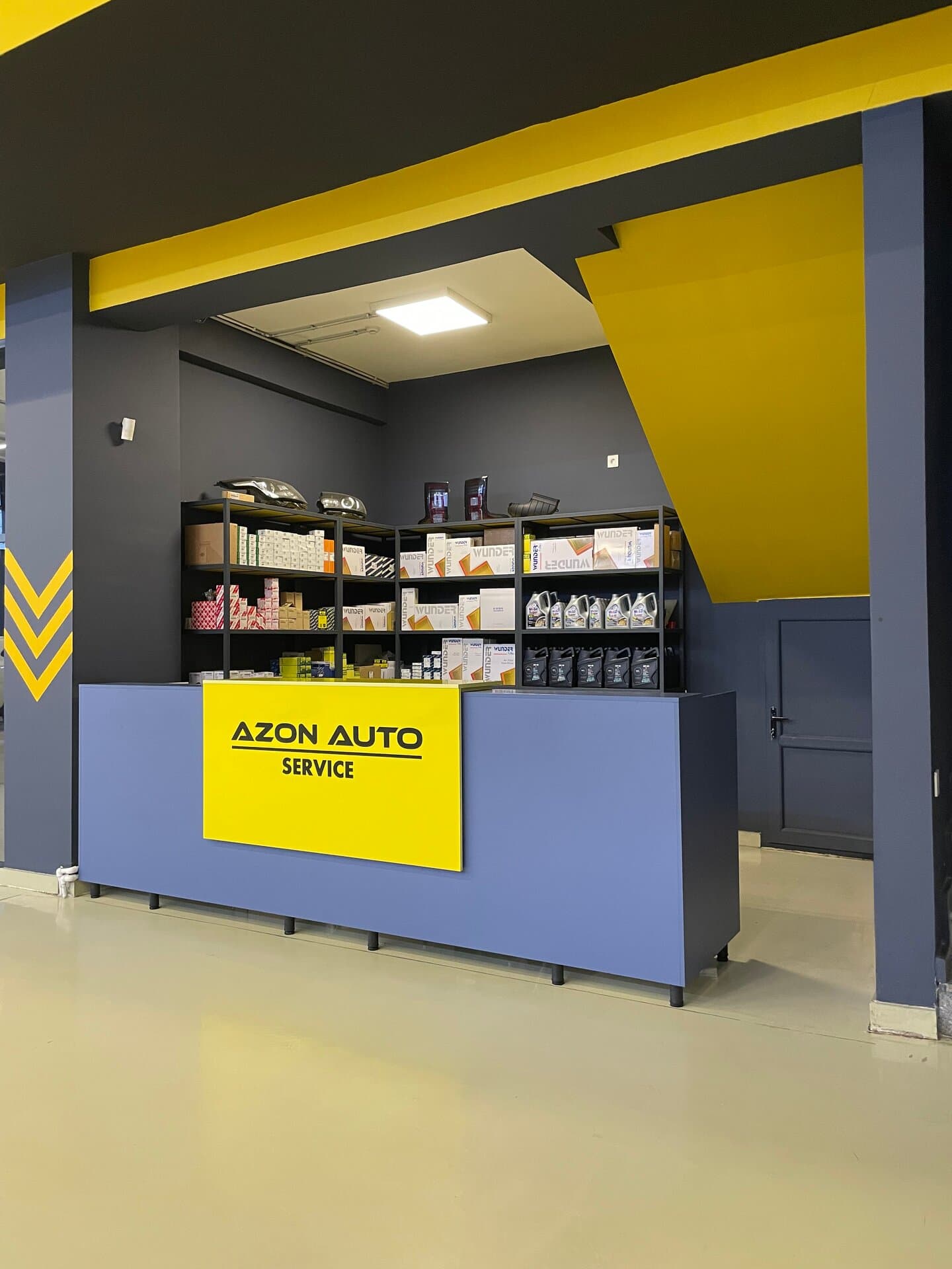 AzonAuto-nun qəbul masası, arxasında yağ və hava filtrləri, mühərrik yağları və faralar olan ehtiyat hissə rəfləri