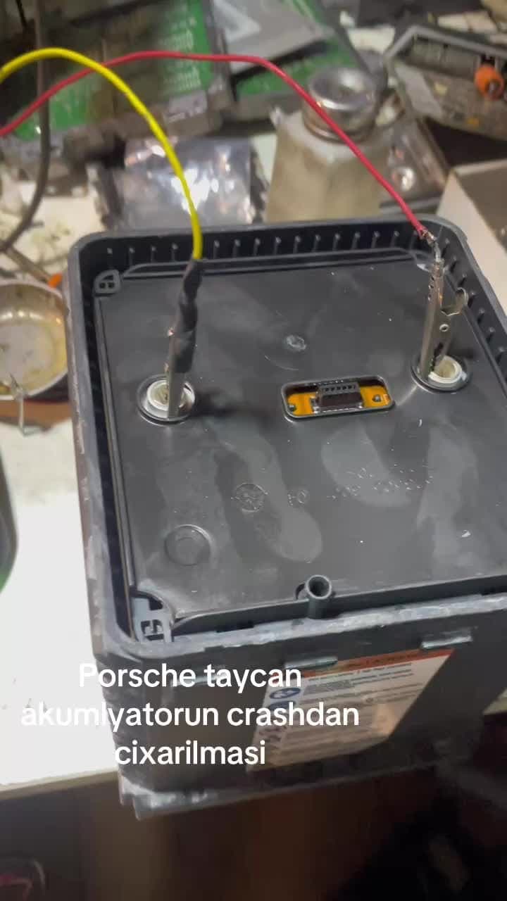 Qəzadan sonra crash vəziyyətində qalmış Porsche Taycan akkumulyator bloku stenddə, naqillərlə qoşulmuş halda.