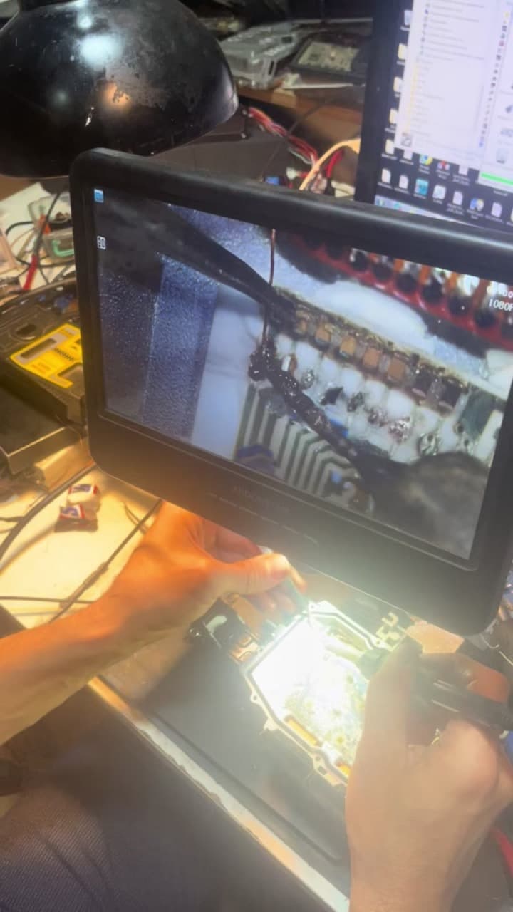 Açılmış modulun platası mikroskop stendinin altında lehimlənir; ekranda kontaktlar böyüdülmüş görünür.