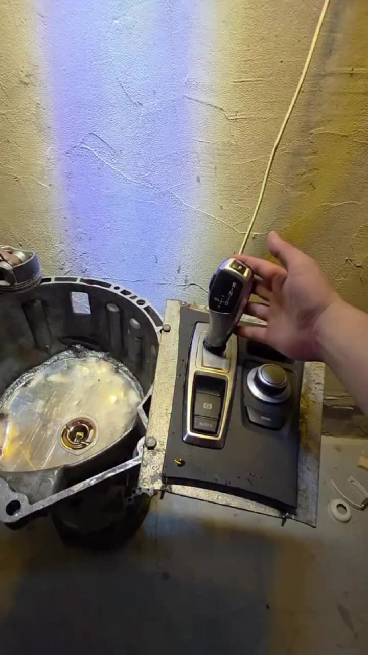 BMW-nin elektron karobka selektoru (P düyməsi ilə) sökülmüş halda, yanında karobka korpusu.