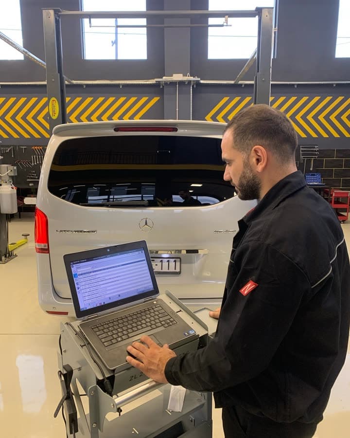 Arxa qapısı açıq gümüşü Mercedes-Benz V-Class (W447), yanında usta noutbukla diaqnostika arabasının arxasında